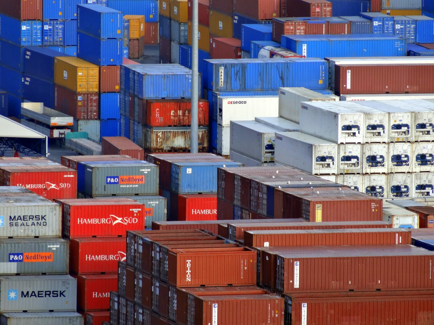 Porto trafficato con centinaia di container marittimi impilati.